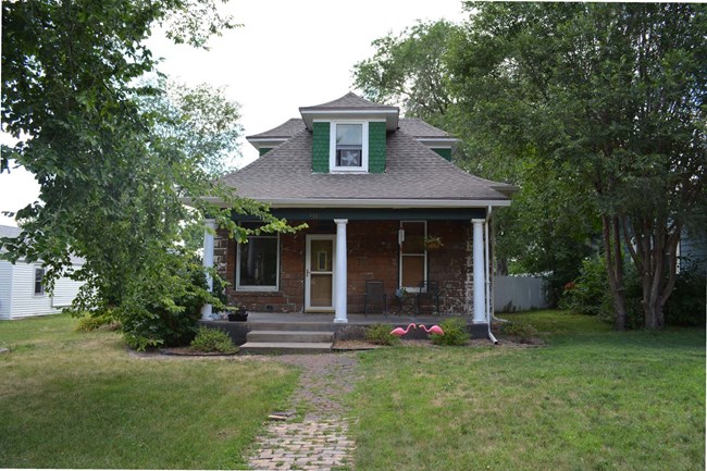 Front view of small one-and-a-half-story concrete block bungalow with 3 columns in front