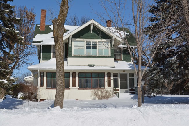 Front of two story house with gabled roof and enclosed porch