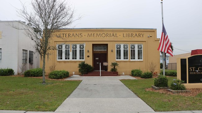 entrance to 1 story building with words engraved on building "Veterans Memorial Library"