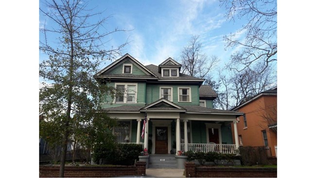 Ruth's Beauty Parlor - three store house with a front porch and supporting columns and stairs walking up to the front door.