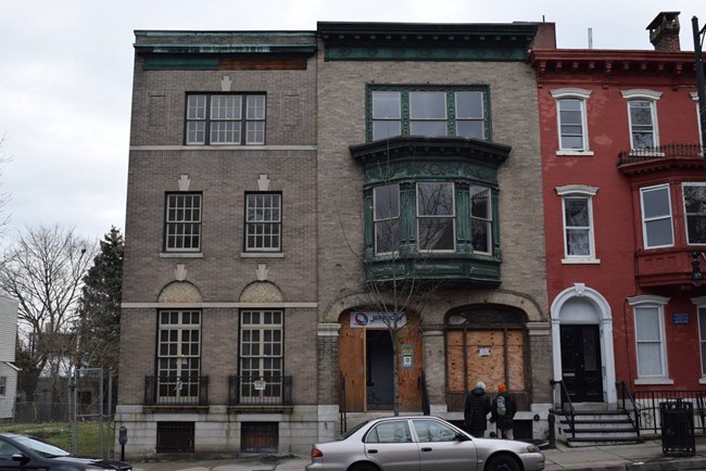 3 story tan brick residential building facing the street