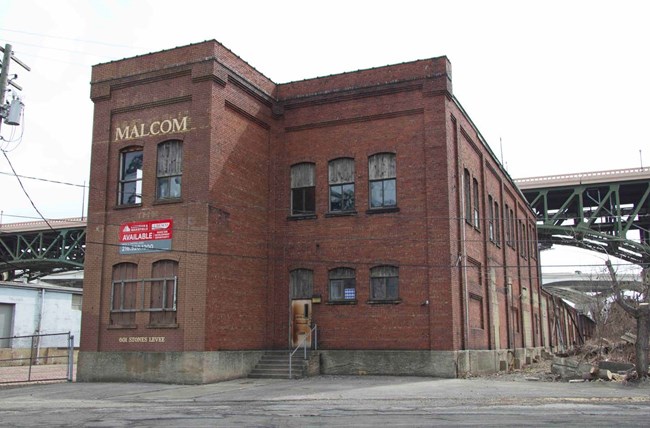 Large two-story brick building showing 5 bays, and large slightly arched windows