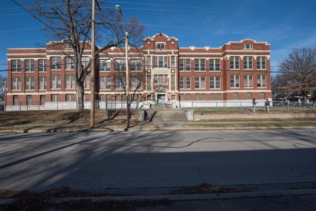 Front entrance to large two story, with raised basement, brick school building