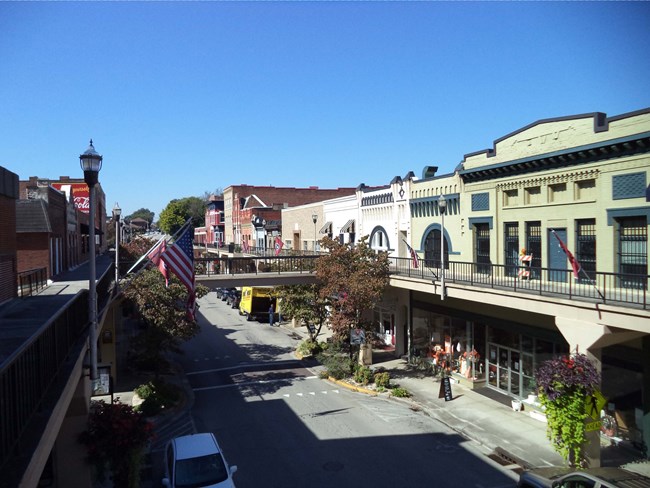 streetscape with two story buildings on either side of street with pedestrian bridge crossing over