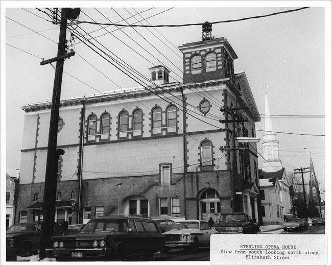 68000040 Sterling Opera House Image of multistory building, cars, road, and electric lines.