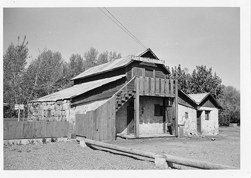 2 story stone building covered with wooden siding