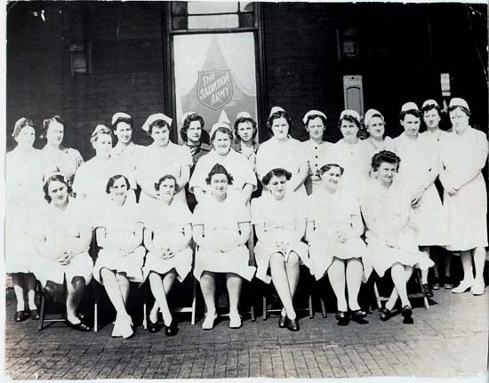 Women sitting and standing in front of Salvation Army sign