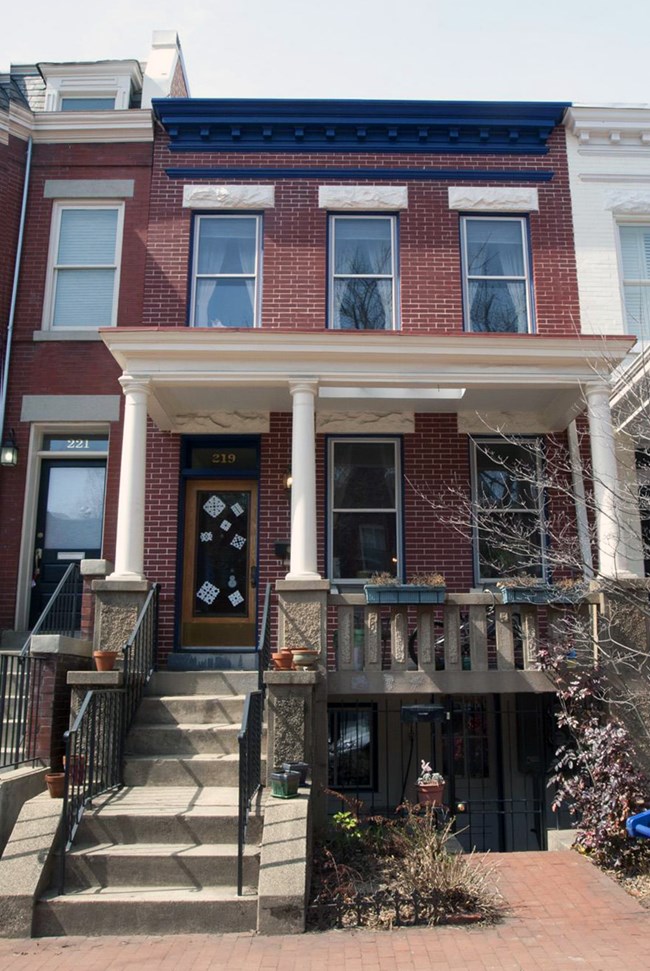 Image of red brick multi-story building with porch.