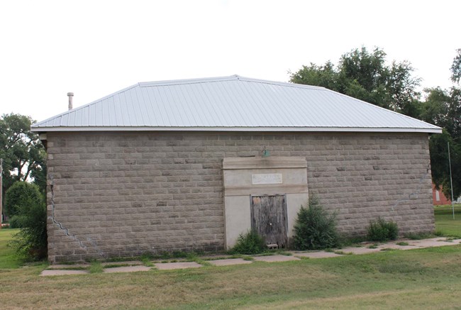 Gray concrete block building, green lawn, and paver pathway.