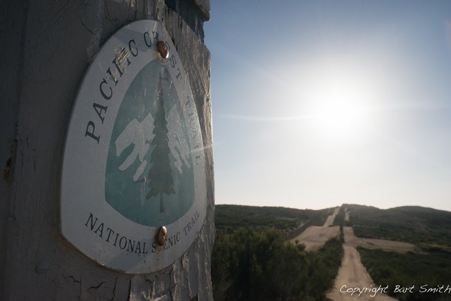 Pacific Crest Trail sign with trail in the background. Pacific Crest Trail sign with trail in the background.