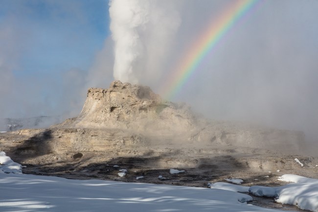 Rainbow over a geyser erupting