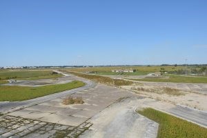 High angle view of three cement pads and a small tan building adjacent to grass covered cement runways.