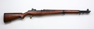 M1 Rifle with dark brown wood butt stock and barrel support, with black metal trigger, sights, and barrel.