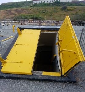 Magazine doors Two bright yellow steel magazine doors one open the other closed are the angled entry to stairs leading underground.