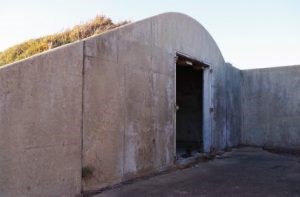Ammunitions Magazine #129 Sloped cement wall with an empty door frame.