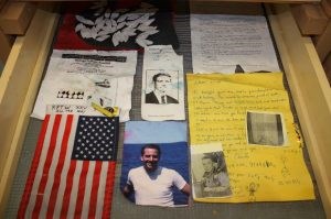 Collage of mementos including flags, photos of young men, hand-written notes, and typed letters.