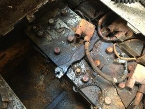 A corroded tank battery with rusted connectors sitting in a deteriorated compartment.