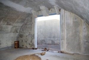 Inside a cement room with a semi-circular wall and large entrance opening.