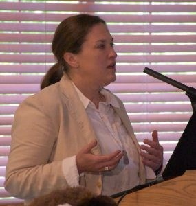 Julie McGilvary White female with hair pulled back in a ponytail wearing a cream-colored jacket over a white shirt.