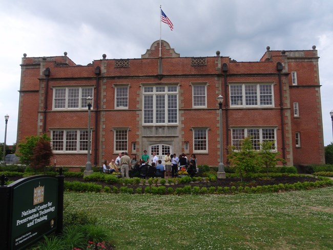 Red brick, two-story building with central steps and door