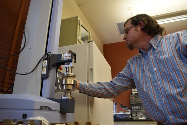 Jason Church uses a universal tester to examine compression strength of mortar.