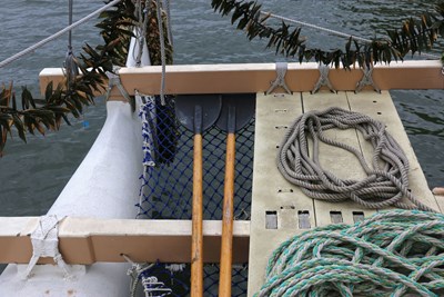 Mālama Honua View of rope rigging, oars and the deck of a boat