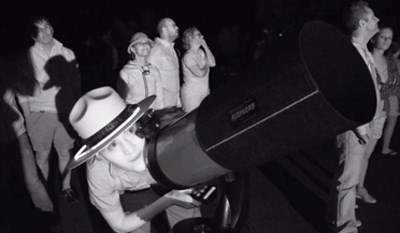 A ranger with Dead Horse State Park looks through a telescope for a view to the night sky.