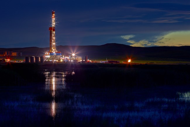 An oil rig drilling site emits bright lights into the atmosphere.