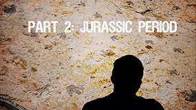 285_Jurassic Final Cut_Moment a rock wall with a silhouette of a person in front. a roaring t rex skull and the words Part 2 Jurassic Period on it