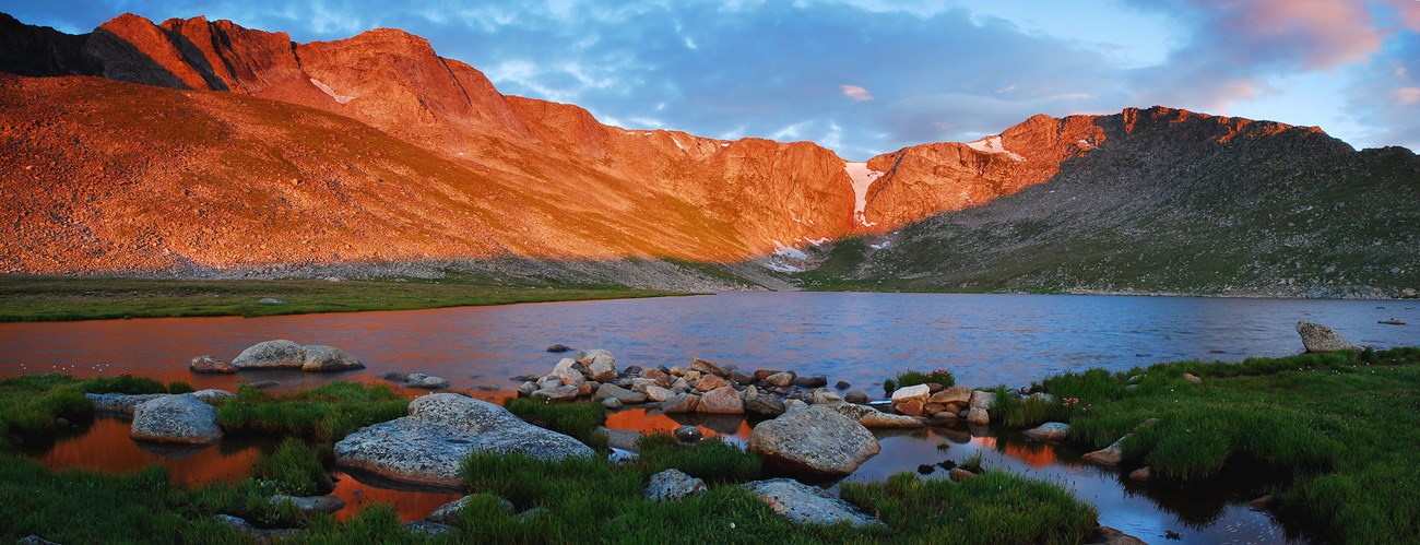 a lake surrounded by red tinged mountains