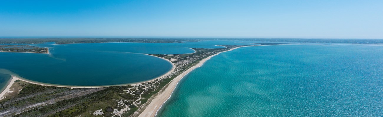 an aerial panoramic view of unique arcing barrier beaches with ocean on either side