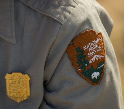 Shoulder of uniformed park employee showing NPS arrowhead and badge