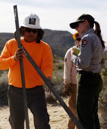 Park rangers work together with volunteers to protect park resources Park ranger and two volunteers install post in desert