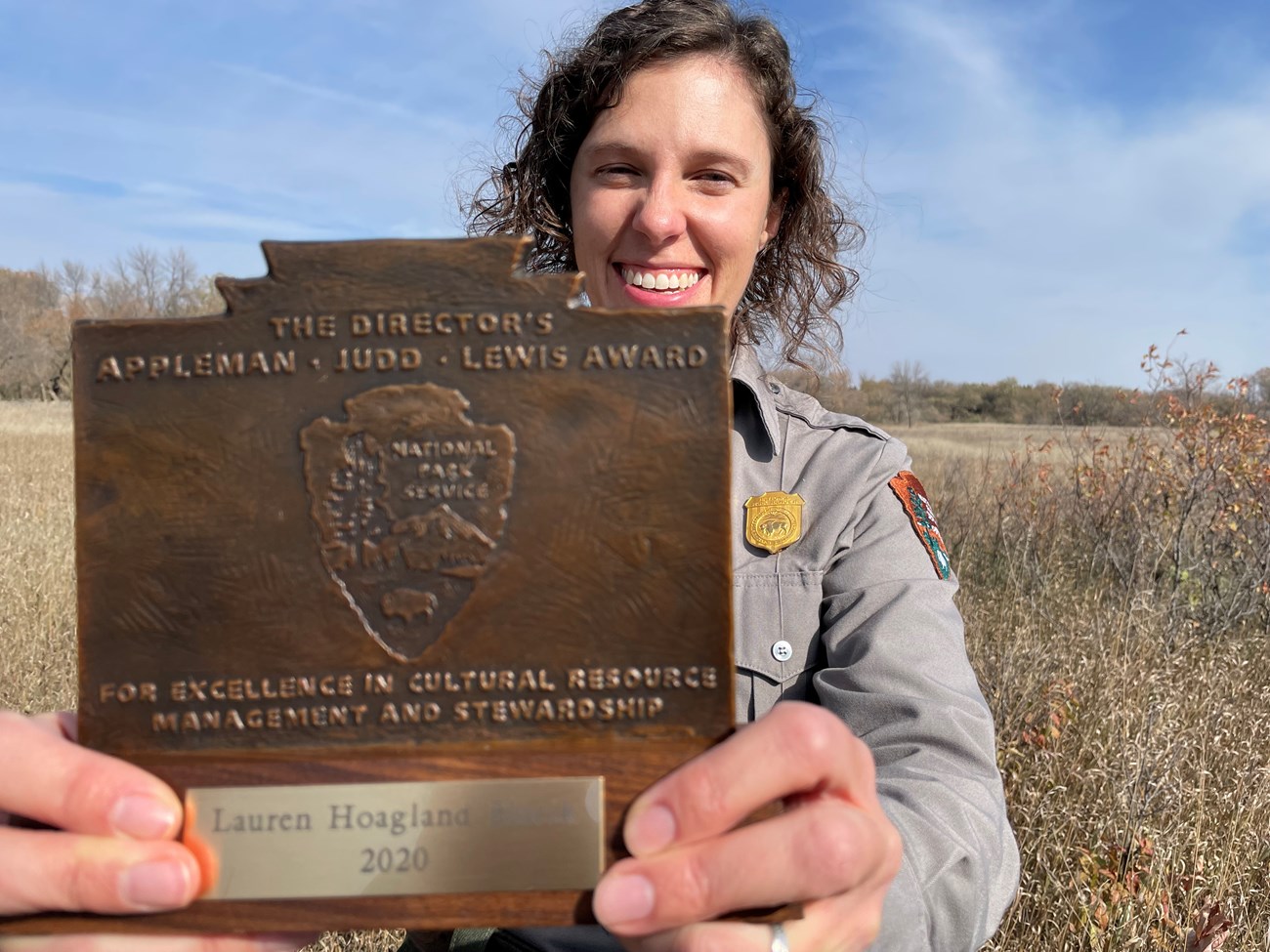 Award winner smiling and holding up her award plaque