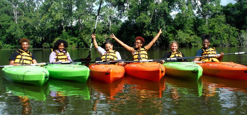 Six girls floating in kayaks and posing for the camera