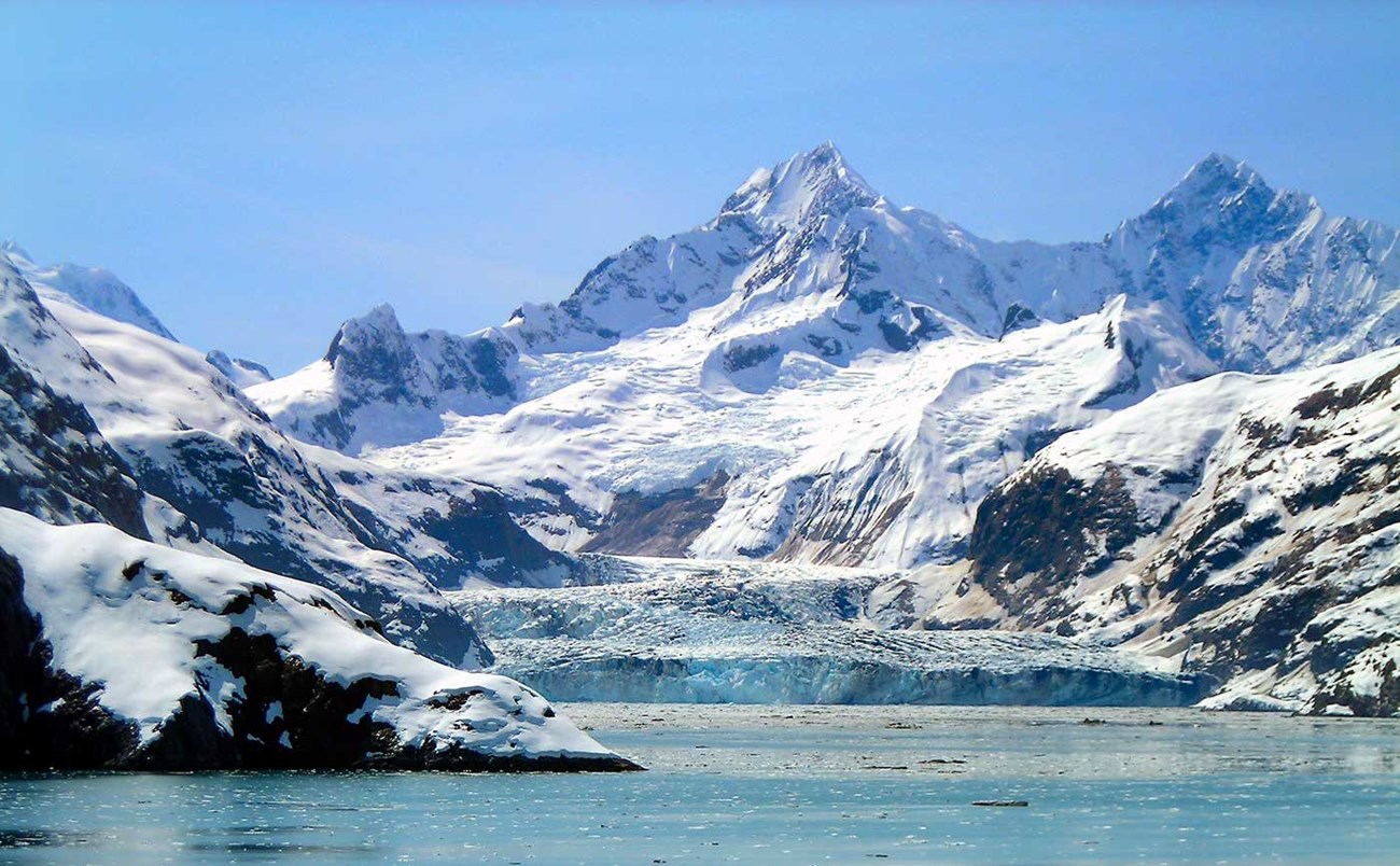 snow-capped mountain rising above ocean bay