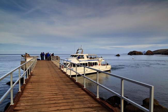 boat docking at pier with visitors walking towards it
