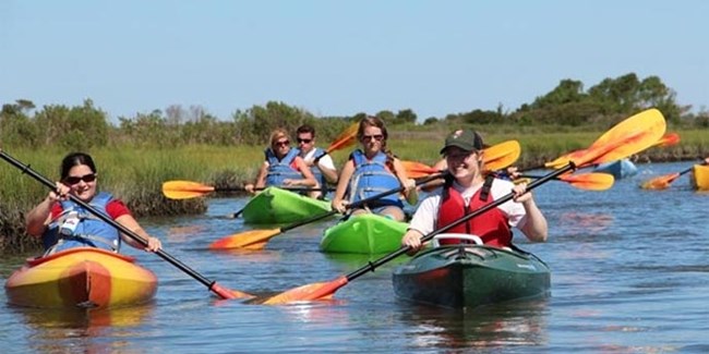 lt= Ranger and visitors kayaking in marsh.