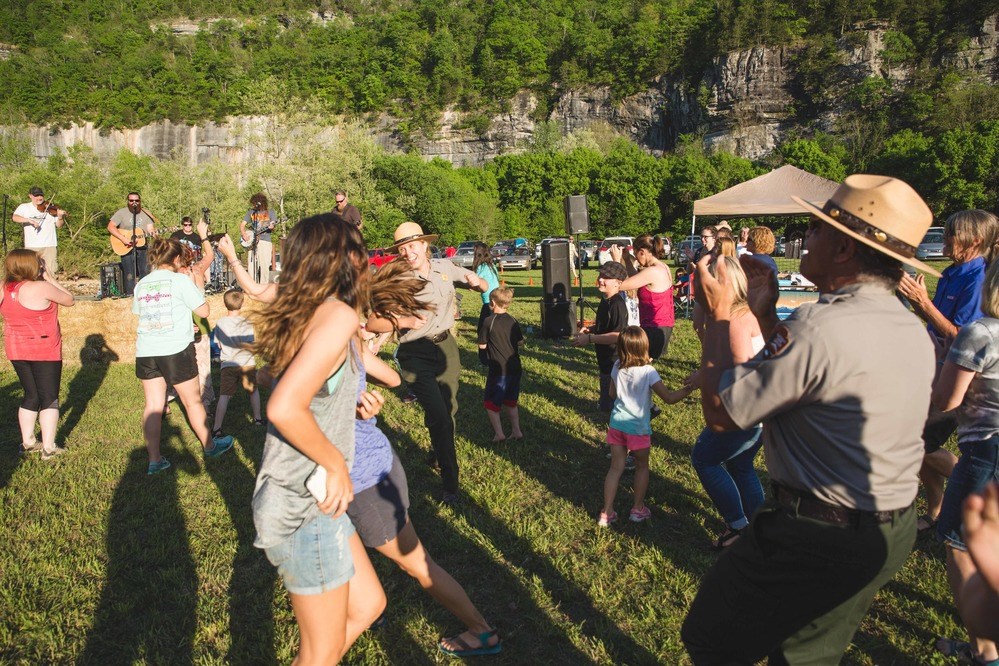 Visitors and park employees dance in the grass in front of a band