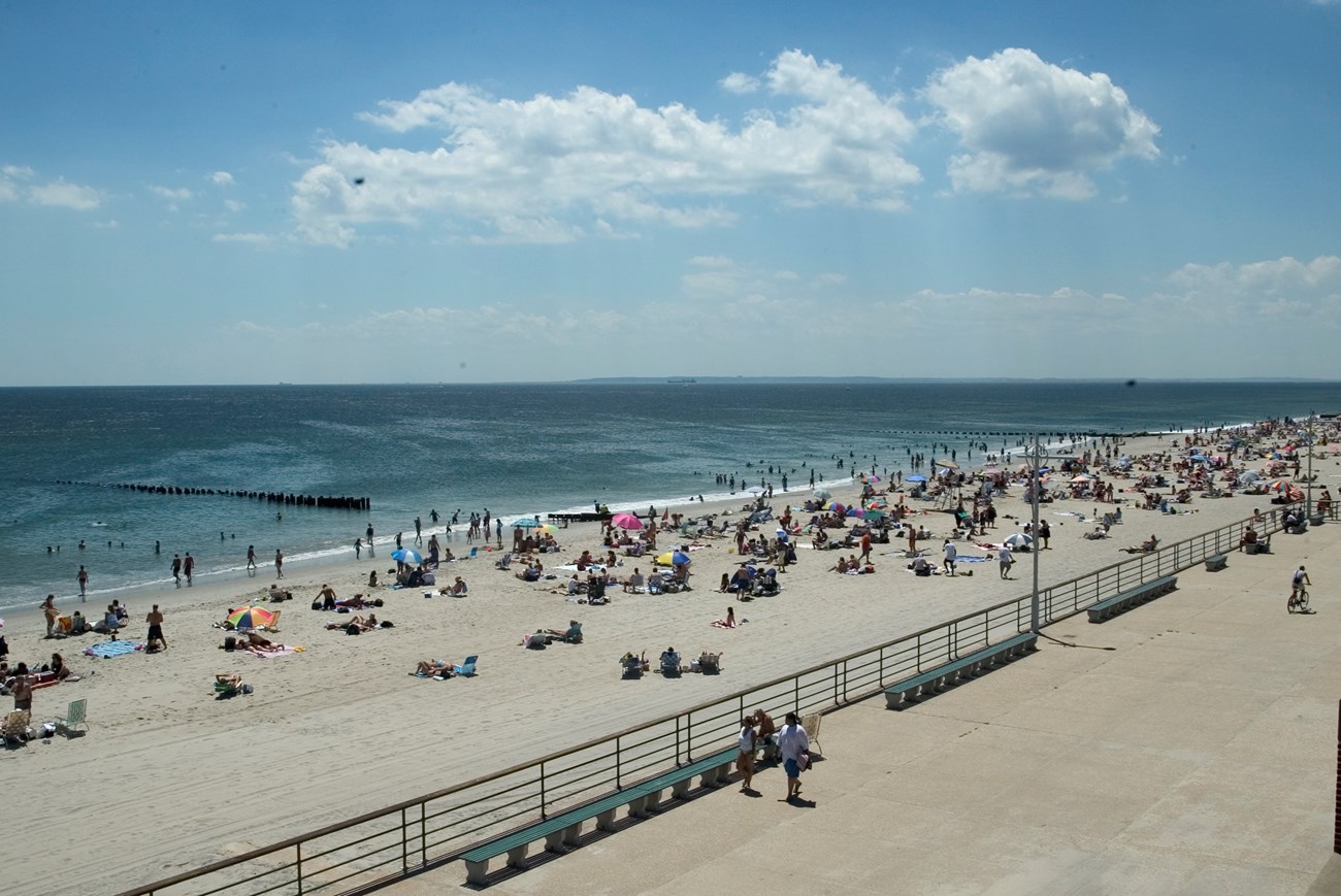 Beachgoers scattered on the sandy beach beside the water at Jacob Riis Park, Brooklyn