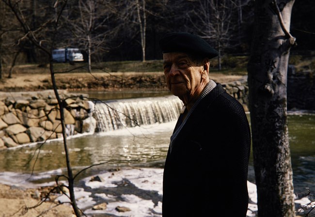 Freeman Tilden standing in front of a waterfall.