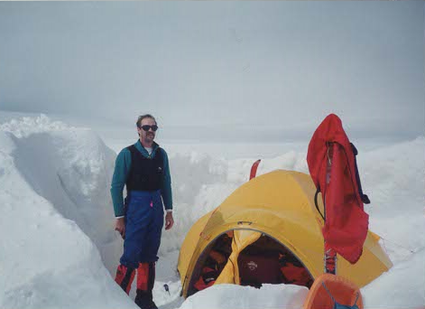 JD Swed stands beside a tent surrounded by high snow banks