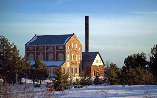 The red brick Quincy Mine Hoist House with tall smoke stack in a snowy landscape
