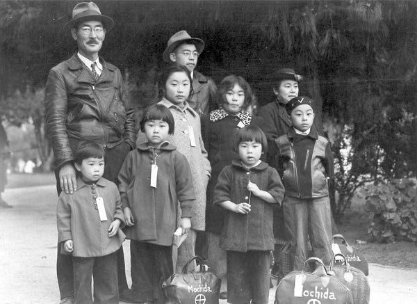 Nine members of the Mochida family, adults and kids, awaiting evacuation bus in 1942.