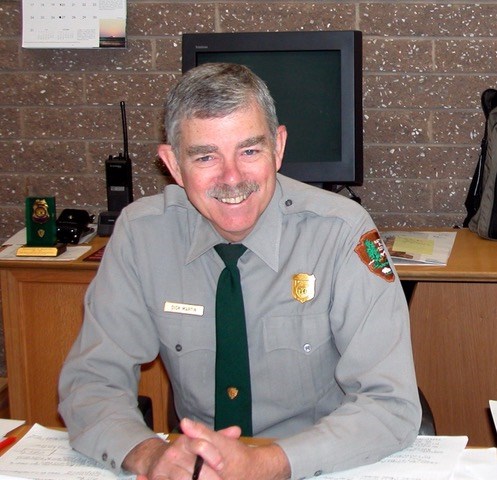 Dick Martin, in NPS uniform with tie, seated behind a desk