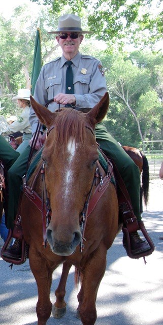 Front view of Dick Martin, in NPS uniform and sunglasses, on horseback.
