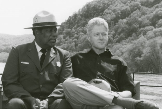 Director Stanton with Bill Clinton in font of water and tree-covered hills