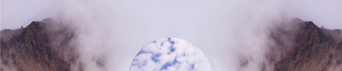 Imaginary landscape with red rocks and wispy white clouds. There is a circular disk between them filled with blue sky and puffy white clouds.