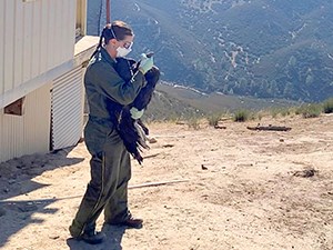 woman in NPS uniform handles a juvenile condor while wearing safety gear