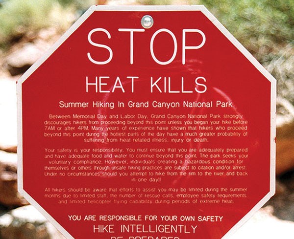 A stop sign with a detailed message about dangers of hiking in hot conditions.